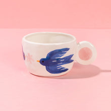 Load image into Gallery viewer, White mug with a blue bird design on a pink background